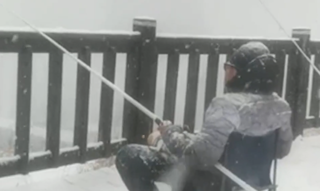 1月6日大连一男子顶着大雪钓鱼 网友：大雪也无法阻挡钓鱼的热情!